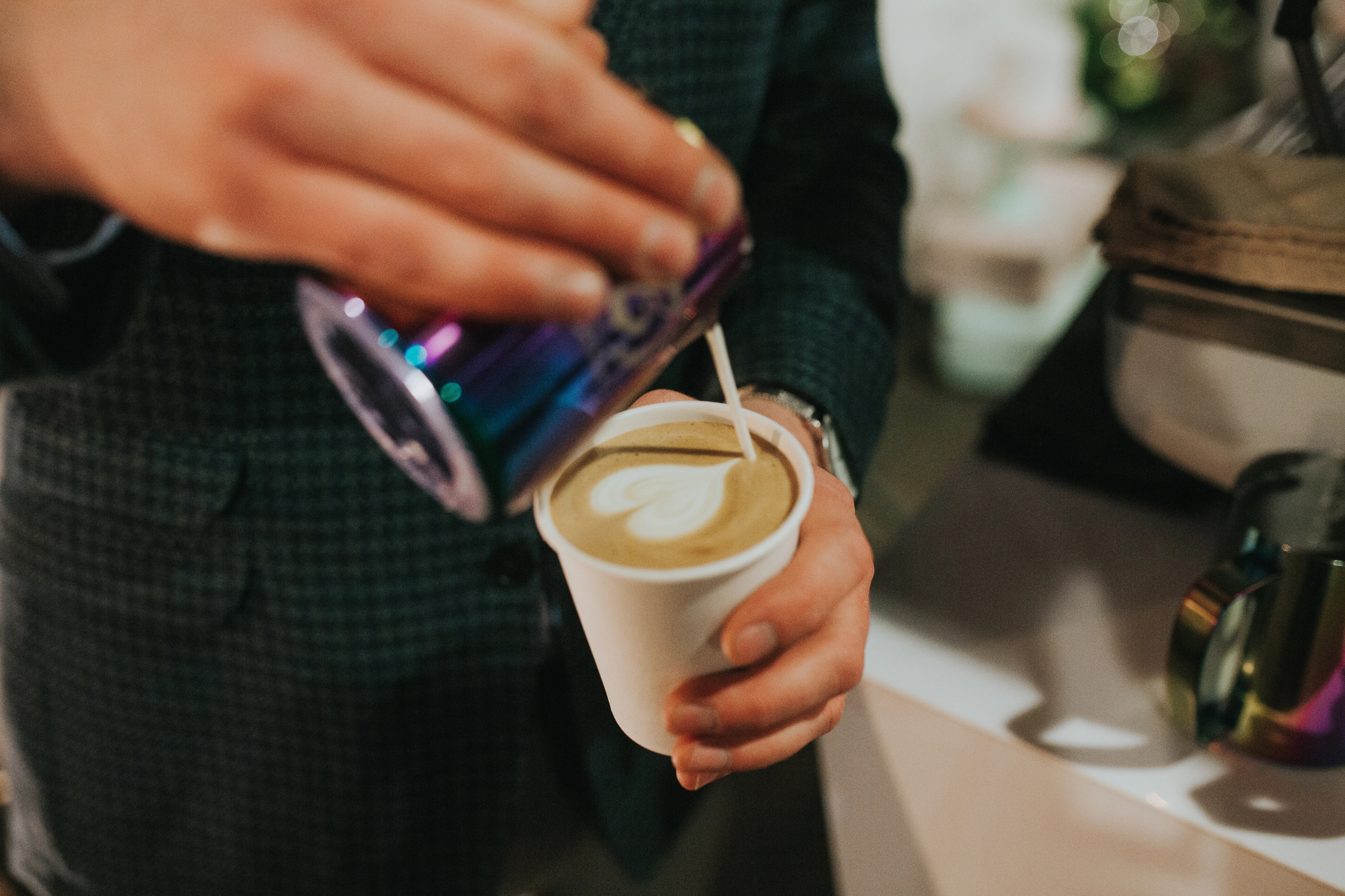Person pouring milk into a coffee cup at an event